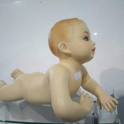 Boneca de plástico a rastejar sobre superfície de vidro com fundo branco