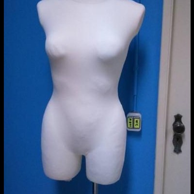Mannequim feminino branco sem cabeça contra parede azul