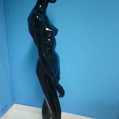 Mannequim feminino preto brilhante em pose lateral contra parede azul