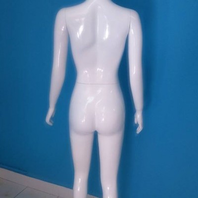 Mannequin feminino branco de costas contra parede azul