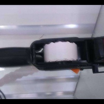 Carimbo de mão preto com fita branca e texto 'RETRAT 1' numa superfície branca com linhas prateadas.