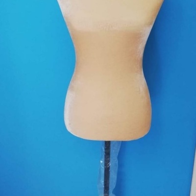 Manequim de costura bege com base preta contra parede azul