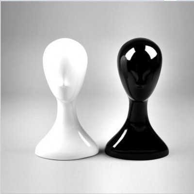 Dois manequins de cabeça em plástico, um branco e um preto, lado a lado.