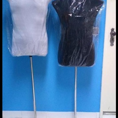 Dois manequins de torso cinzento claro e preto com suporte metálico em fundo azul