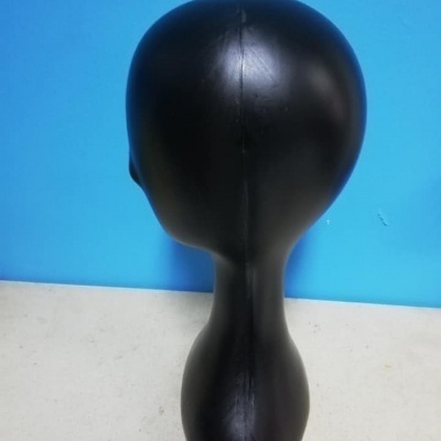 Cabeça de manequim preta com costura central em fundo azul.