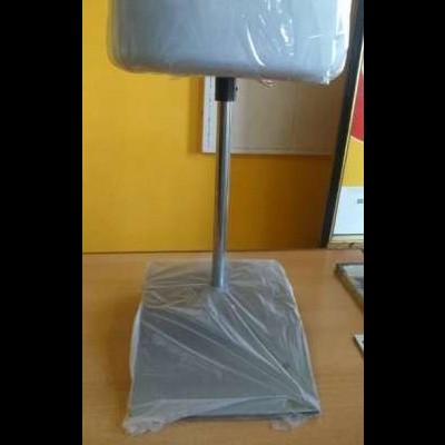 peça metálica cinzenta com base quadrada embrulhada em plástico sobre mesa de madeira