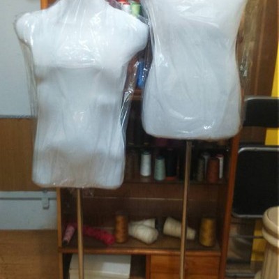 Dois manequins de costura femininos brancos cobertos por plástico em estúdio de costura