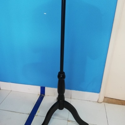 Suporte trípode em madeira preta com pernas arqueadas em chão de azulejos