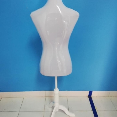 Manequim de torso feminino branco com base trípode branco contra parede azul