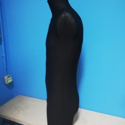 Manequim preto de torso masculino sem cabeça numa superfície branca e fundo azul