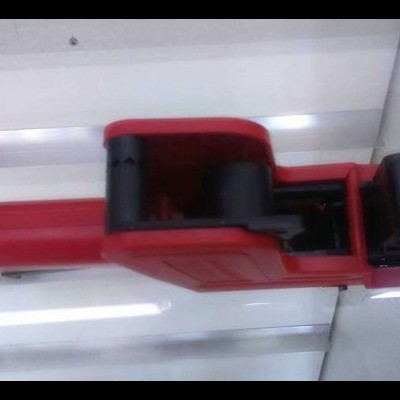 Pistola manual vermelha e preta com contador numérico em superfície branca