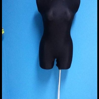 Manequim feminino preto com base metálica contra parede azul.