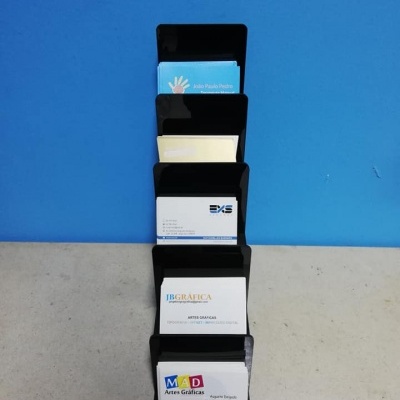 Suporte preto com cartões de visita sobre mesa com fundo azul