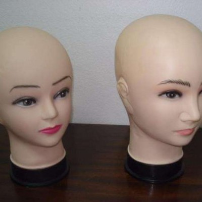 Duas cabeças de manequim em plástico bege sobre superfície de madeira escura