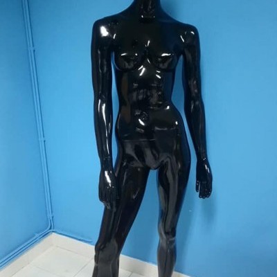 Manequim feminino preto brilhante em pé num ambiente interior com paredes azuis