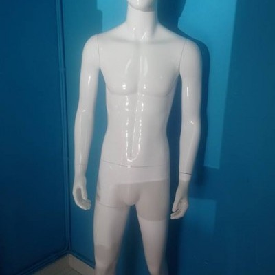 Mannequim masculino branco em pé junto a parede azul