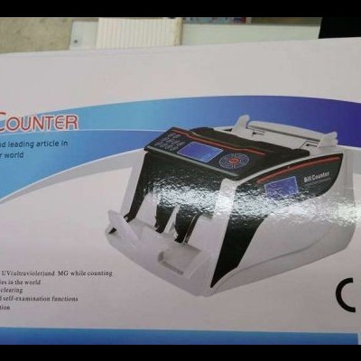 Máquina de contar dinheiro preta e cinza numa caixa com texto em inglês