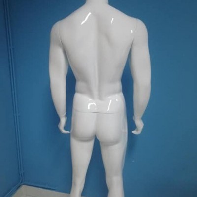 Mannequin masculino branco visto de costas contra parede azul
