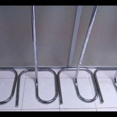 Seis suportes metálicos cromados para pendurar objetos em fila sobre piso branco