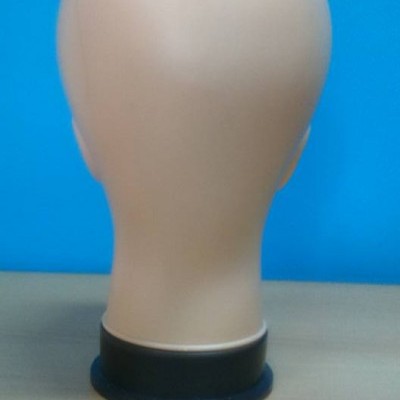 Cabeça de manequim bege de plástico numa base preta sobre mesa clara