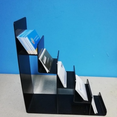 Expositor de cartões de visita preto com cinco níveis sobre superfície clara e fundo azul