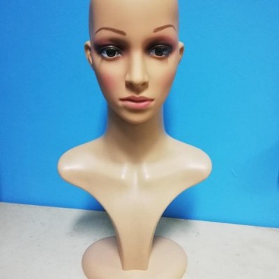 Bust de manequim feminino em plástico cor bege sobre superfície clara com fundo azul