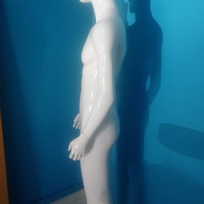 Manequim masculino branco em suporte quadrado num canto com paredes azuis