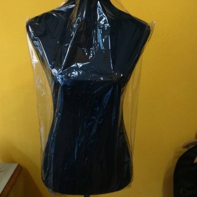 Mannequim preto coberto com plástico transparente em fundo amarelo