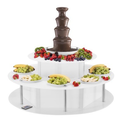Fonte de chocolate com frutas frescas variadas numa base branca com várias tigelas