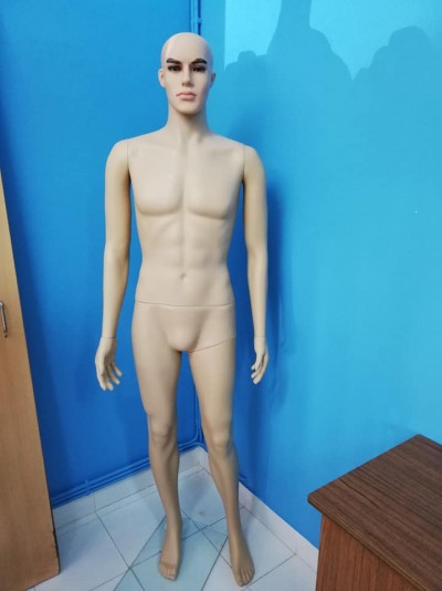 Manequim masculino cor bege em pé contra parede azul em canto de sala