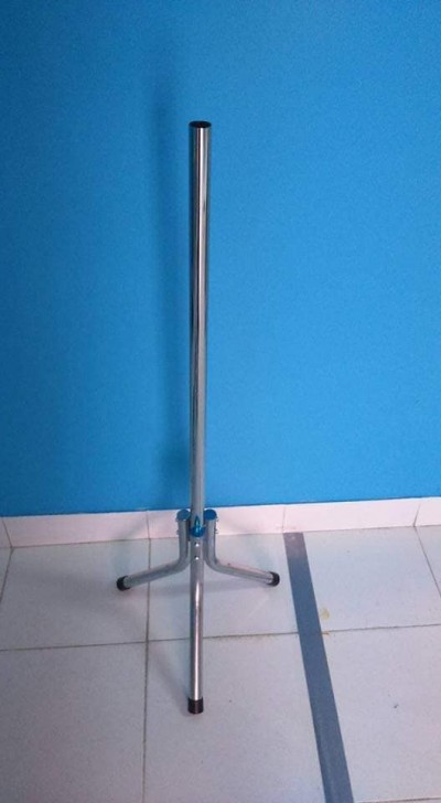 Suporte metálico com três pernas e ligação azul, sobre chão branco e parede azul