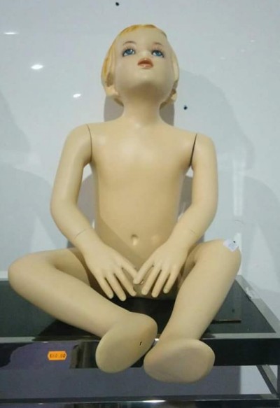 Boneco manequim infantil sentado, pele creme e cabelo loiro, olhos azuis