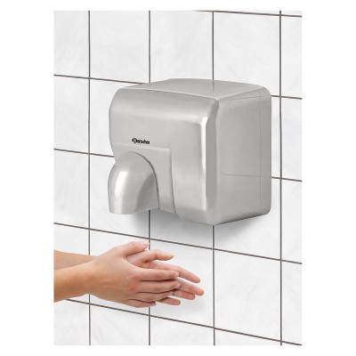 Secador de mãos automático de metal prateado montado na parede com azulejos brancos.