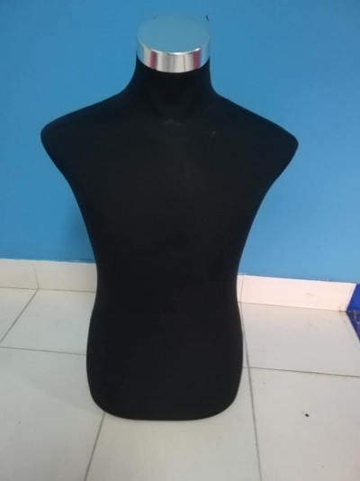 Manequim de torso preto com topo prateado em chão de azulejos brancos e parede azul