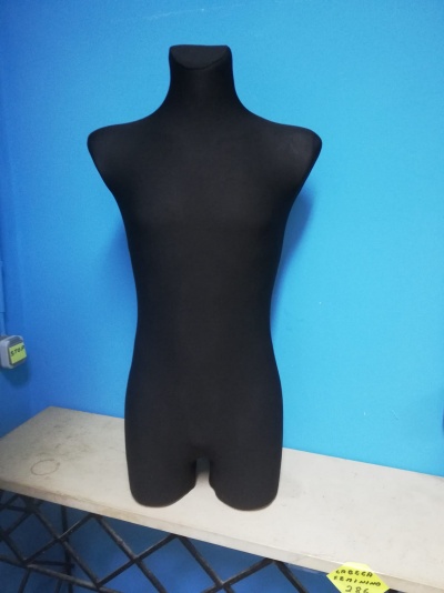 Mannequin torso in black on table against blue wall