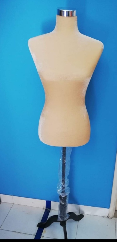 Manequim de costura bege com base preta contra parede azul