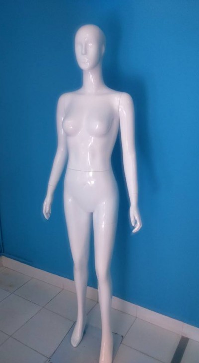 Mannequim feminino branco contra parede azul