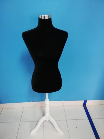 Manequim de costura preto com base branca em frente a parede azul