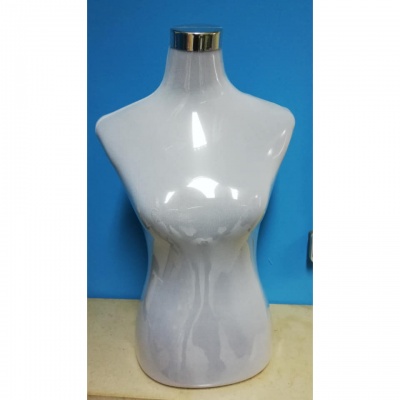 Manequim busto feminino branco com topo metálico sobre superfície bege