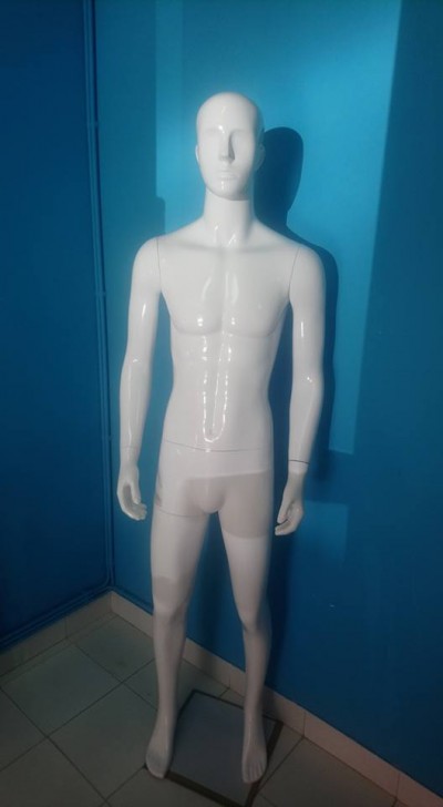 Mannequim masculino branco em pé junto a parede azul