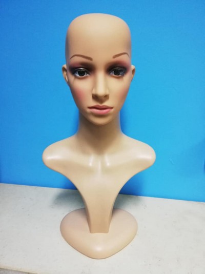 Bust de manequim feminino em plástico cor bege sobre superfície clara com fundo azul