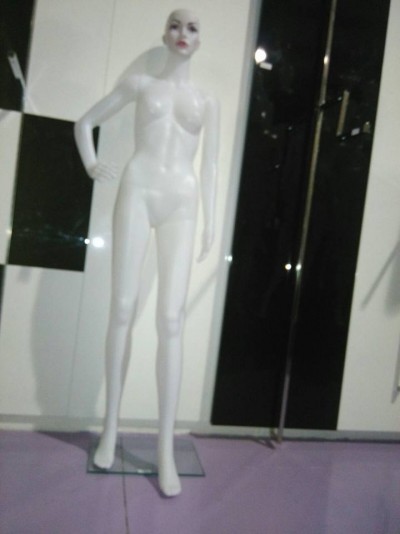 Mannequim feminino branco com rosto pintado em pé sobre base de vidro transparente