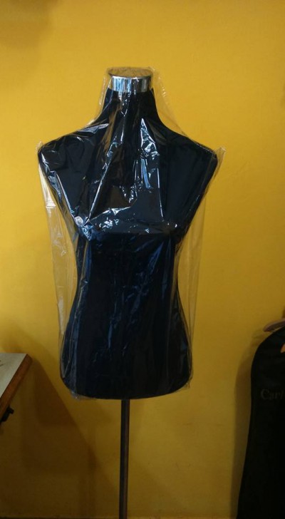 Mannequim preto coberto com plástico transparente em fundo amarelo