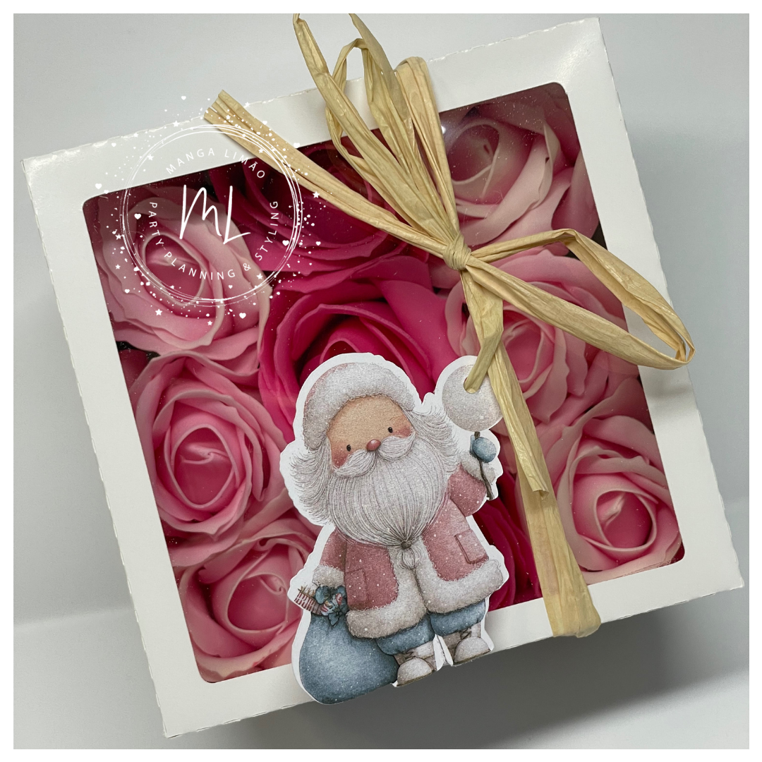 Caixa branca com rosas artificiais rosas e etiqueta com desenho de Pai Natal