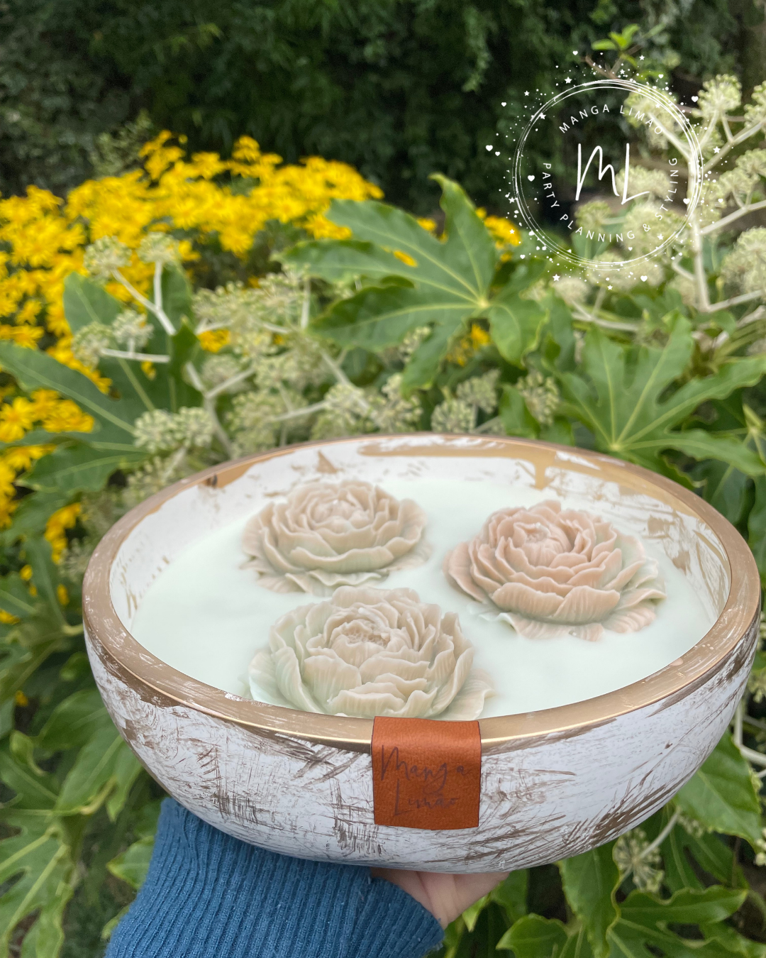 Taça decorativa com flores esculpidas flutuando em líquido branco num ambiente natural