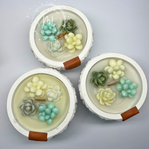 Velas decorativas com flores coloridas em recipientes brancos redondos com detalhe em pele