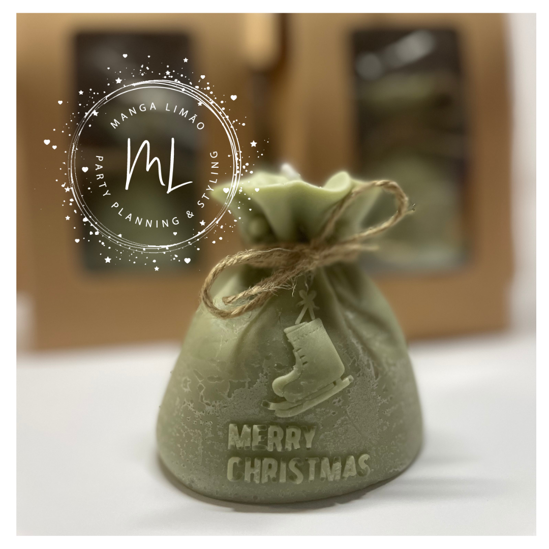 Vela em forma de saquinho verde com texto Merry Christmas e imagem de bota de Natal