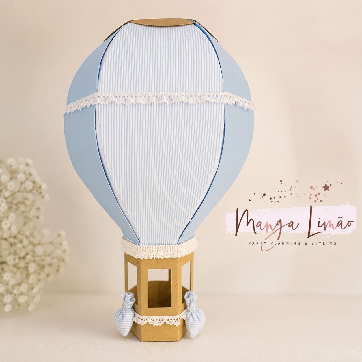 Modelo decorativo de balão de ar quente azul claro e branco com base em cartão castanho.