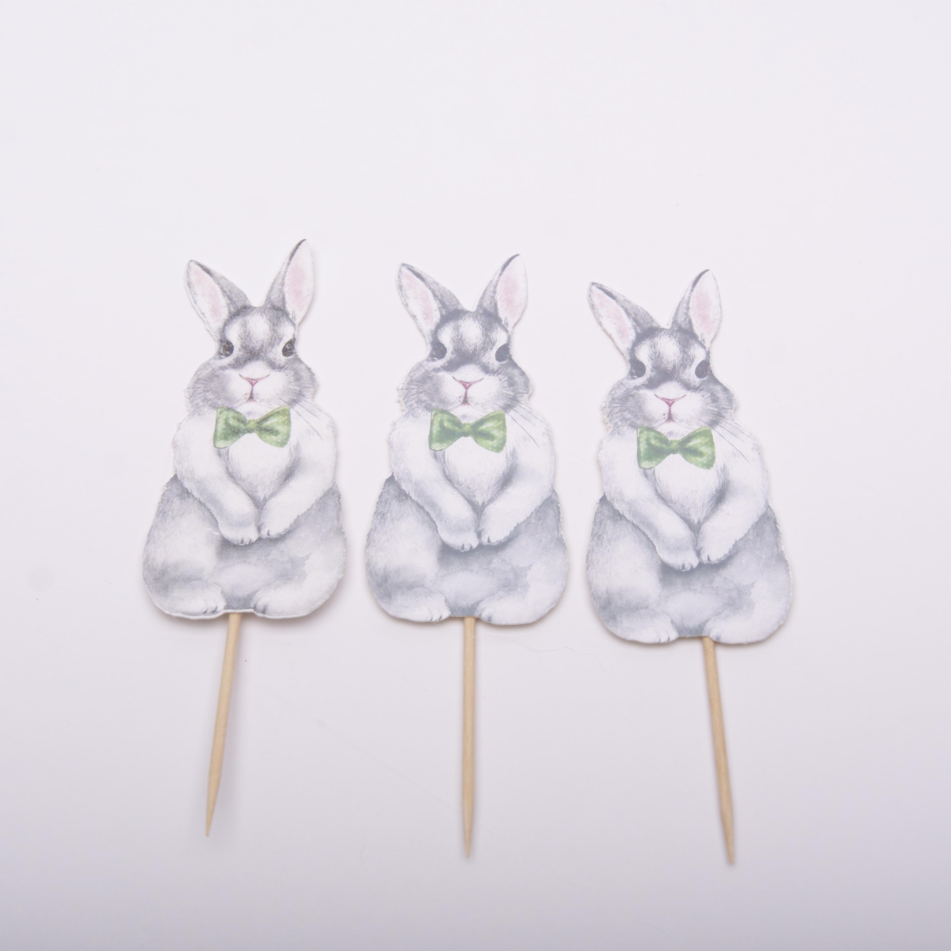 Três toppers de bolo com coelhos cinzentos e gravata borboleta verde