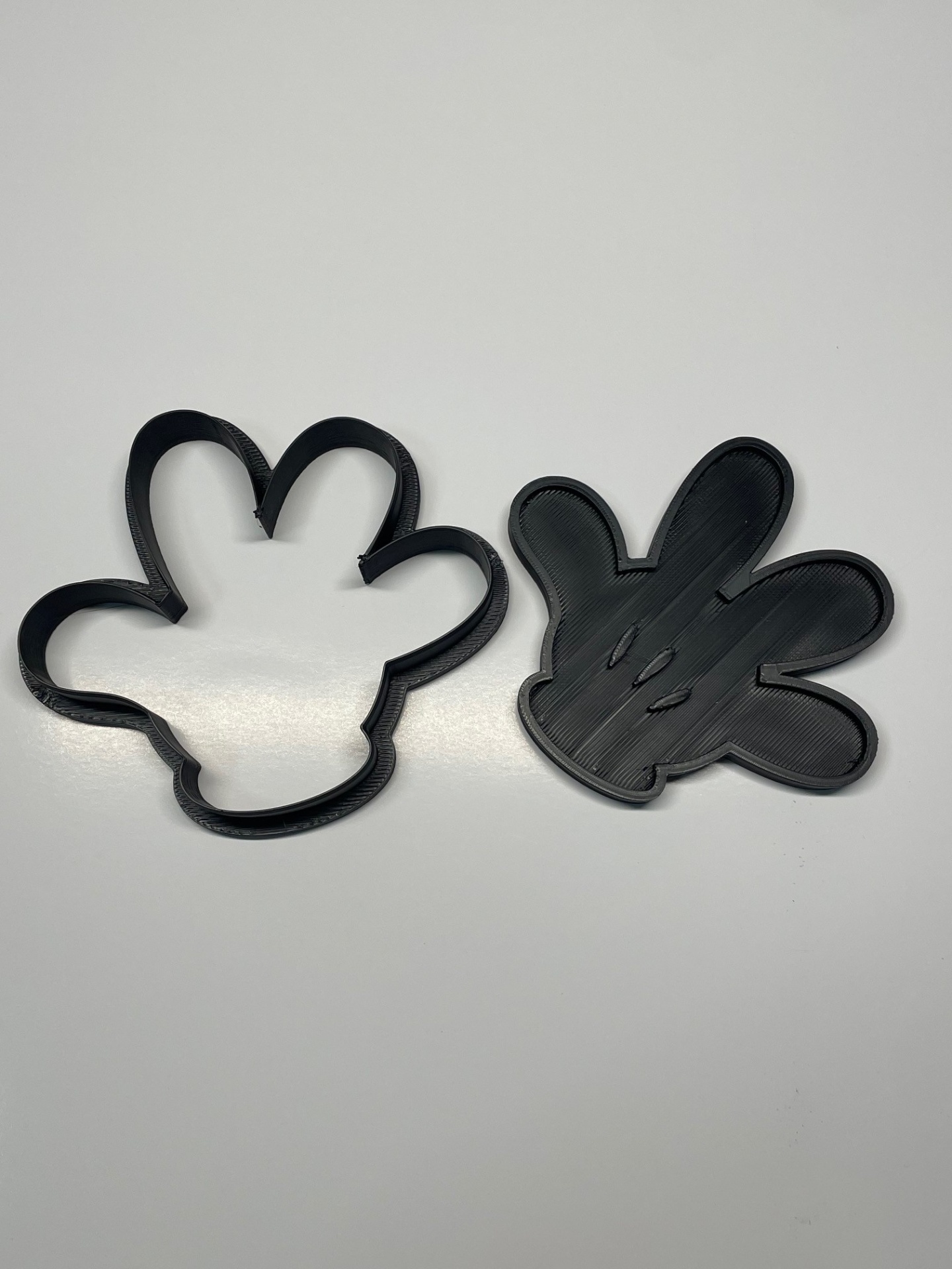 Dois cortadores de bolachas pretos em forma de mão cartoon numa superfície branca